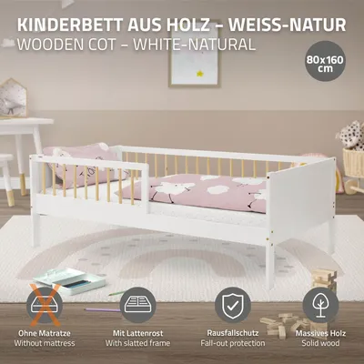 A white and natural wood children's bed with pink bedding, set in a room with a rug and a small table.