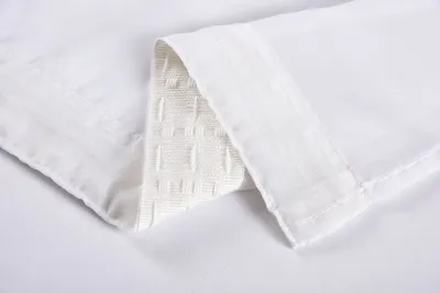 A close-up of white fabric, likely a curtain, folded to show texture and stitching.