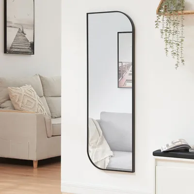 A modern living room with a couch and a tall, narrow mirror.