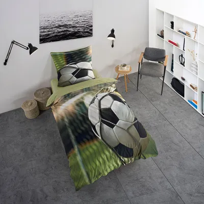 A bedroom scene with a bed featuring football-themed bedding, a chair, and a bookshelf.