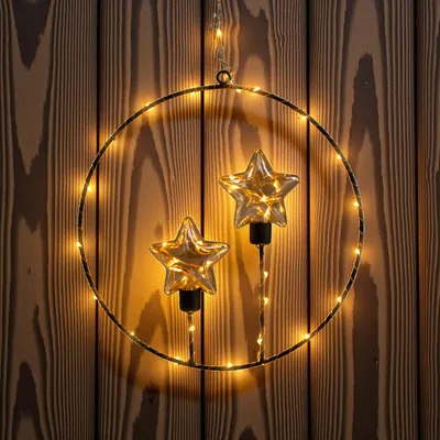 A decorative wreath with LED lights and star-shaped bulbs hanging against a wooden background.