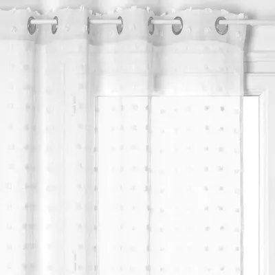 A close-up view of a white sheer curtain with a dotted pattern, hanging from a curtain rod.