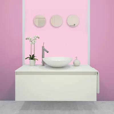 A modern bathroom vanity with a vessel sink, faucet, orchid plant, and soap dispenser, set against a pink wall.