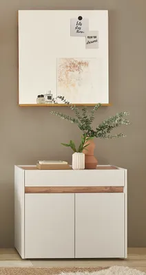 A modern white and wood dresser with a shelf above it, decorated with plants and artwork.