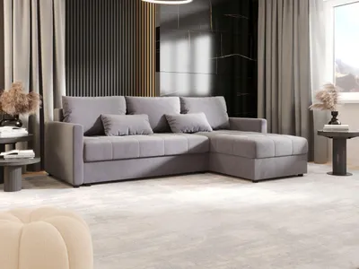 A modern living room with a gray sectional sofa, curtains, and decorative elements.