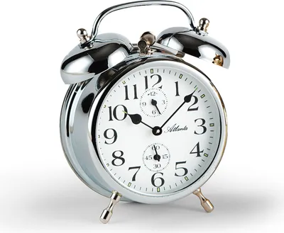 A close-up studio shot of a silver analog alarm clock against a white background.