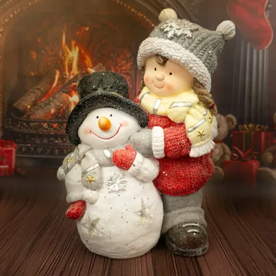 A decorative figurine of a girl hugging a snowman in front of a fireplace.