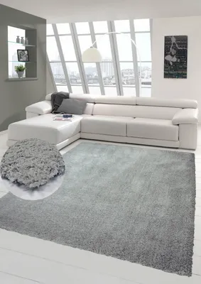 A modern living room with a white sectional sofa and a gray shaggy rug.