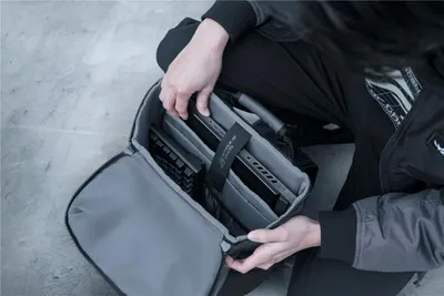 A person is packing a laptop into a backpack.