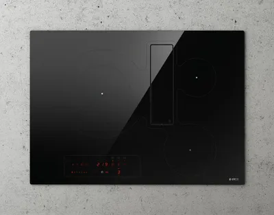 A black induction hob with an integrated extractor fan, shown from a top-down perspective on a textured gray background.