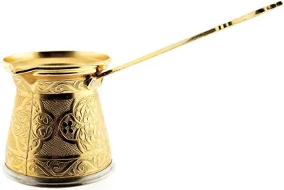A golden coffee pot with intricate carvings and a long handle, isolated on a white background.