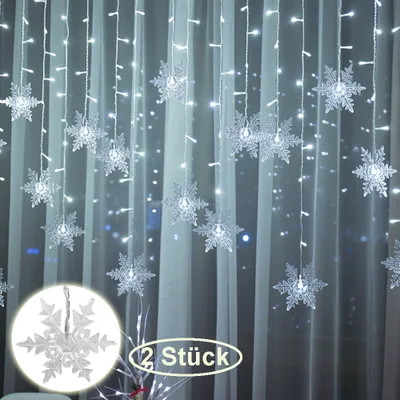 A curtain of snowflake-shaped lights hanging against a sheer white curtain.
