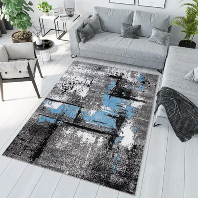 A modern living room with a sofa, armchair, and a rug.