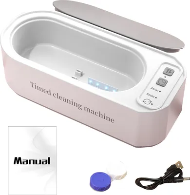 A white ultrasonic cleaning machine with a gray lid, shown with a manual, a contact lens case, and a USB cable.
