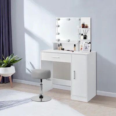 A white vanity table with a lighted mirror and a gray stool in a room.