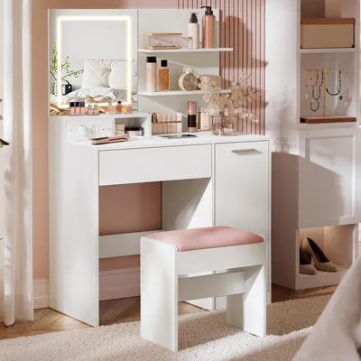 A white vanity table with a lighted mirror, makeup, and a stool in a room.