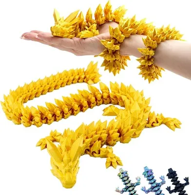 A person's hand and arm are holding a yellow, segmented dragon figurine. Another segmented dragon figurine is laid out on a white surface below. Smaller, multi-colored dragon figurines are in the bottom right corner.