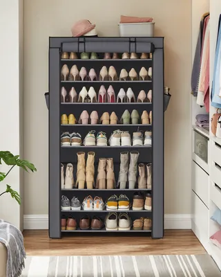 A tall, gray fabric shoe organizer filled with various shoes and boots, positioned in a room with a wooden floor and a striped rug.