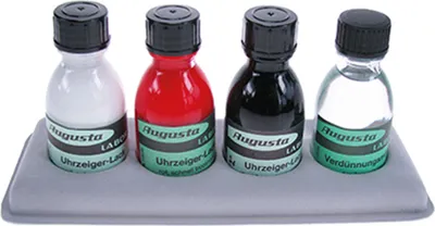 Four small bottles of colored lacquer and a clear liquid are arranged in a gray holder.