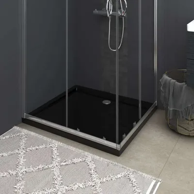 A black shower tray inside a shower enclosure, with a rug in the foreground.