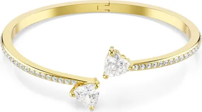 A gold-colored cuff bracelet with clear heart-shaped stones at the ends and clear stones along the band.