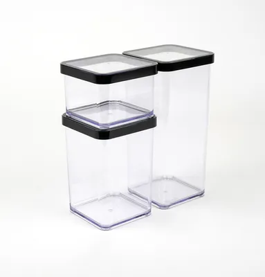 Two clear plastic food storage containers with black lids are shown against a white background. One container is taller than the other, and a smaller container is stacked on top of the shorter one.