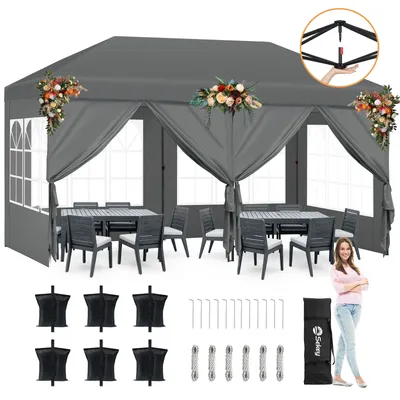 A pop-up gazebo set up with tables and chairs, decorated with floral arrangements, and accessories laid out below.