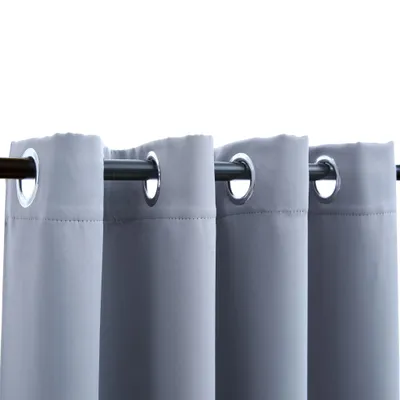 A close-up view of gray curtains with metal grommets hanging from a curtain rod.