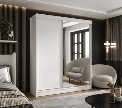 A bedroom scene featuring a white wardrobe with a mirrored door, a bed, and chairs.