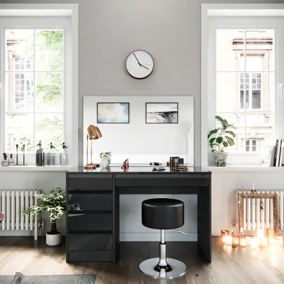 A vanity table with a stool and drawers, set up in a room with windows and a radiator.