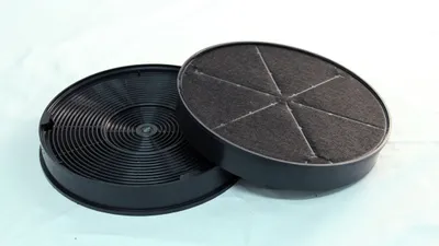 Two circular charcoal filters for a range hood, one on top of the other, against a light background.