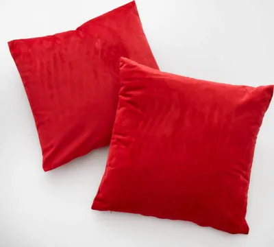 Two red square pillows are placed on a white background.