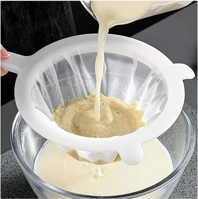 Liquid being strained through a fine mesh sieve into a glass bowl.