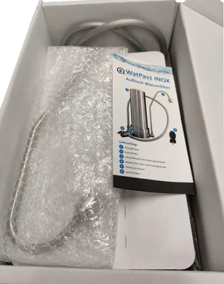 The image shows the contents of a product box, including a water filter and its accessories, along with an instruction manual.