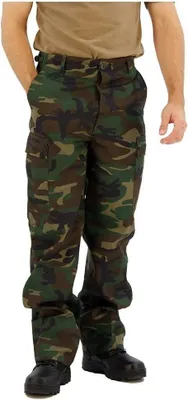 A person wearing camouflage pants and a tan shirt, standing against a white background.