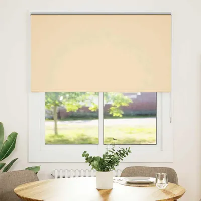 A roller blind is shown covering a window in a room, with a table and chairs in the foreground.