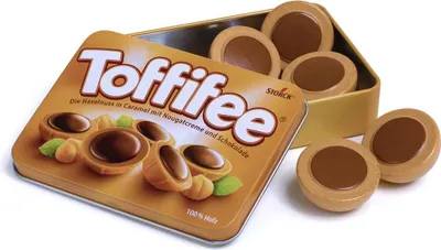 A tin of Toffifee candies is shown with some candies outside the tin.