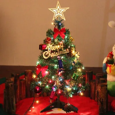 A decorated Christmas tree on a red mat with wooden fence accents.