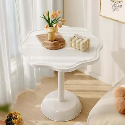 A white side table with a flower vase and tissue box on top, placed near a window with sheer curtains.