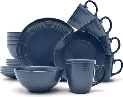 A collection of dark blue stoneware dishes and mugs are neatly stacked and arranged against a white background.