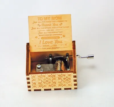 A wooden music box with a message engraved on the lid, sitting on a white background.