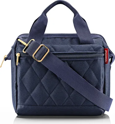 A studio shot of a navy blue quilted shoulder bag with gold hardware.