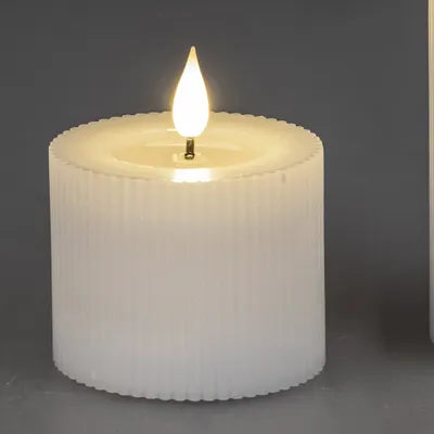 A close-up of a white LED candle with a flame.