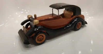 Handgefertigtes Holzmodell eines Oldtimers. Das Auto ist hauptsächlich aus braunem Holz gefertigt.
