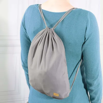 A person wearing a blue sweater and a gray drawstring backpack.