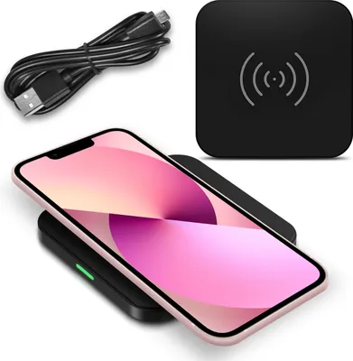 A smartphone is wirelessly charging on a black charging pad, with a USB cable in the background.