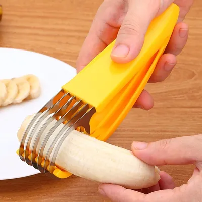 A person is using a yellow banana slicer to cut a banana. Sliced bananas are visible on a white plate.