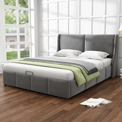 A bedroom scene with a grey upholstered bed, dressed with white bedding, a green throw blanket, and a grey and white patterned blanket.