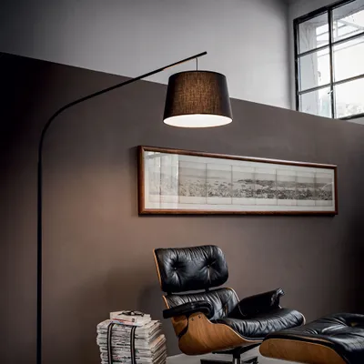 A modern living room with a black floor lamp, a leather armchair, and a framed artwork on the wall.