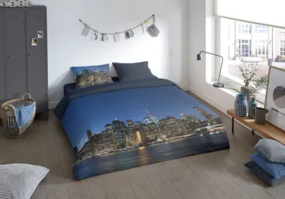 A bedroom scene with a bed featuring a New York City skyline duvet cover.